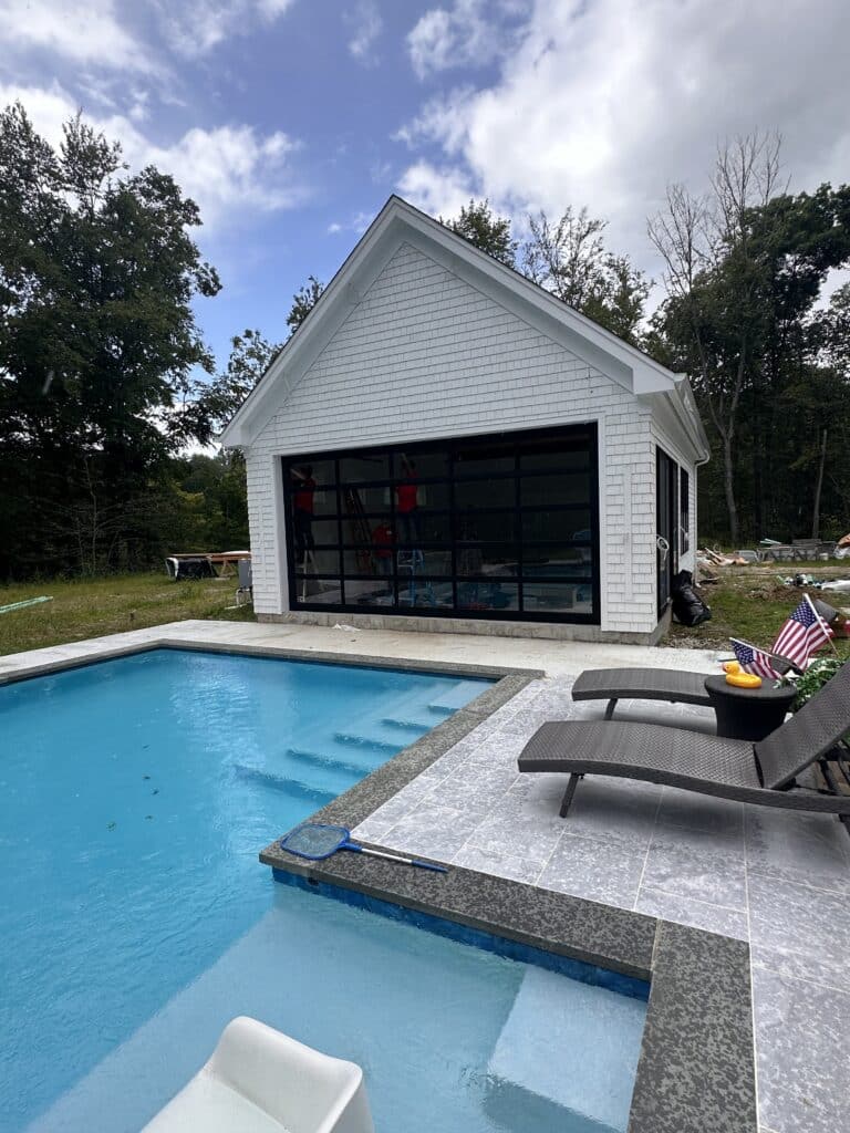 Modern glass garage door on a white detached garage
