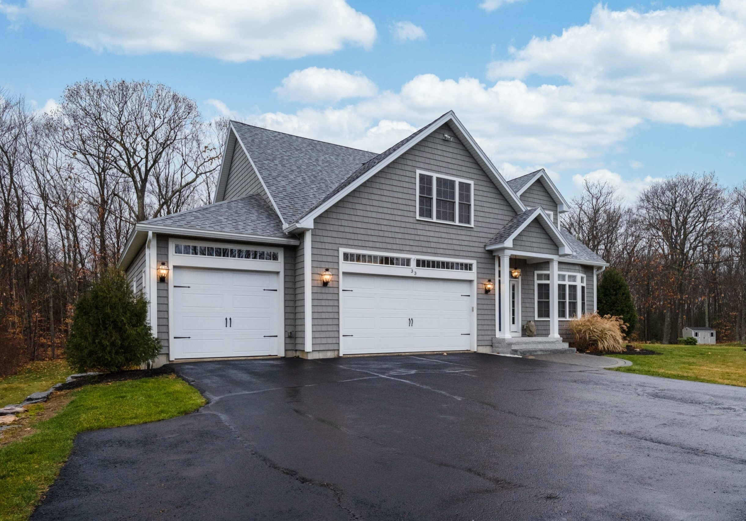 A gray-walled suburban house with white asphalt driveway